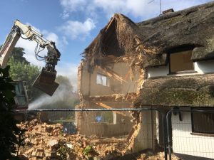 House being demolished by a machine